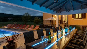 Ein Essbereich im Freien mit Pool, Liegestühlen und einer überdachten Terrasse.