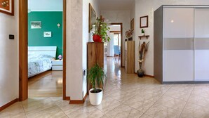 Ein Flur mit einem Bett, einer Zimmerpflanze, einem Holzschrank und einem Kleiderschrank.