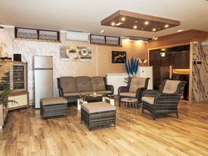 A modern living room with a sofa set, two armchairs, a coffee table, and a dining table. There is a built-in air conditioning unit, a decorative wall piece, and a potted plant. - Villa Helena by Interhome (Pićan)