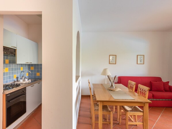 A compact living space with a kitchen, dining area, and a red sofa.