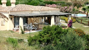Una villa con techo de tejas, mobiliario exterior y piscina.