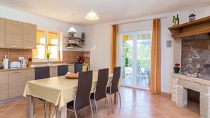 A modern kitchen with a dining area, a stone fireplace, and a view of the outdoors. - Vacation home Antoni by Interhome (Pićan)