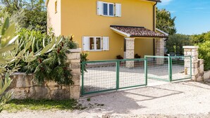 A yellow building with a tiled roof, white shutters, and a green gate. - Vacation home Antoni by Interhome (Pićan)