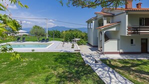 A two-story building with a swimming pool, a garden, and a view of mountains. - Vacation home Carlo by Interhome (Pican)