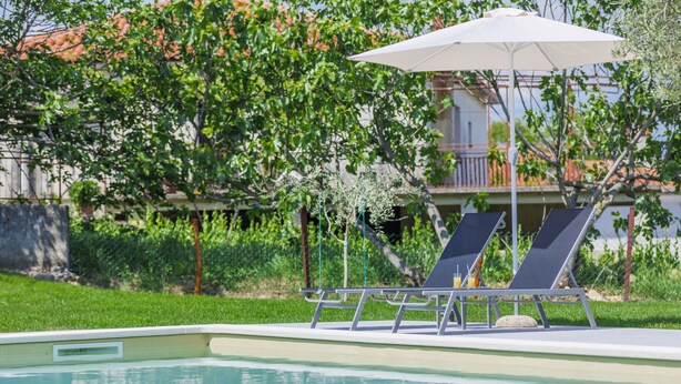 A swimming pool with two lounge chairs and a sun umbrella. - Vacation home Carlo by Interhome (Pican)