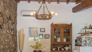 A rustic kitchen with a wooden table, chairs, a stone wall, a chandelier, a cabinet with glass doors, and a refrigerator covered in magnets. - Il Casaletto by Interhome (Lago di Vico)