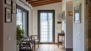 A hallway with wooden beams, a door with glass panels, framed pictures, and a potted plant. - Il Casaletto by Interhome (Lago di Vico)