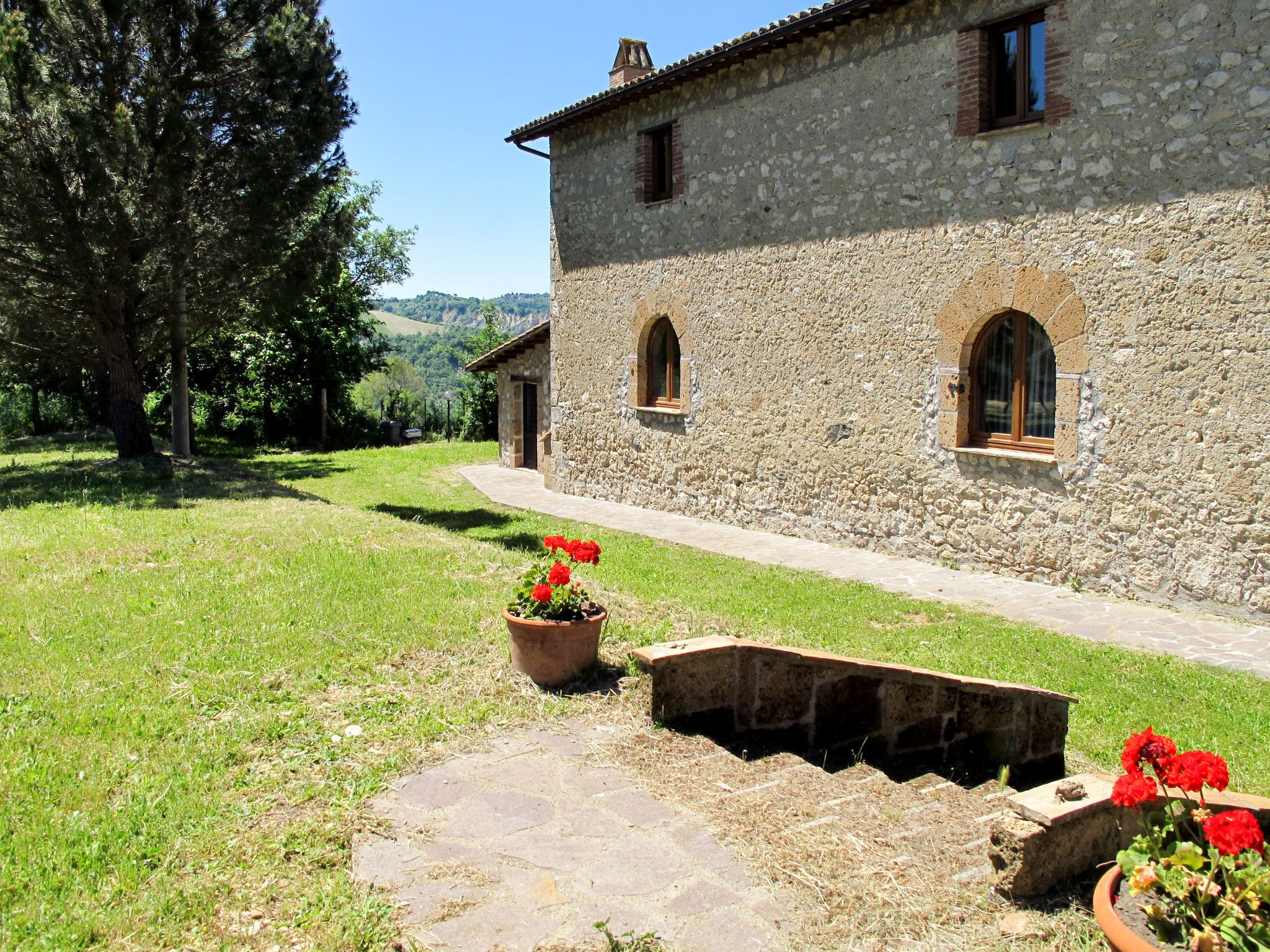 A stone building with arched windows and a paved pathway leading to it.
