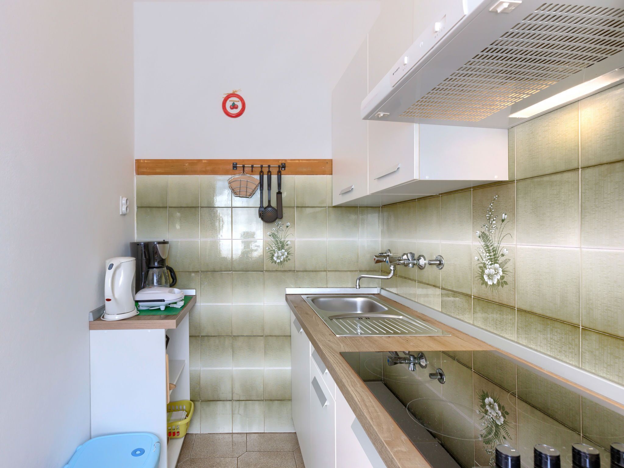 Cocina compacta con un lavamanos, una cafetera y un pequeño cubo de basura.
