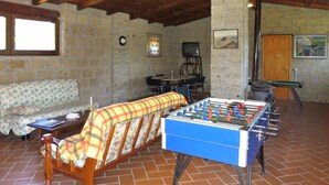 Una habitación acogedora con una mesa de fútbolín, un sofá, un televisor y un piano.