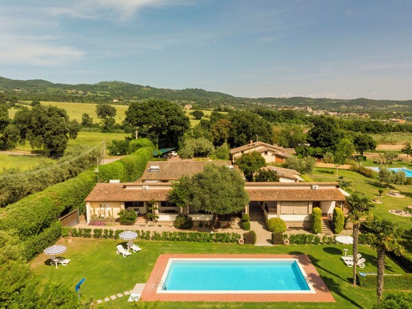 Une villa avec piscine, entourée d’une végétation luxuriante et de collines.