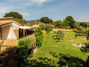 Une villa dotée d’un espace extérieur aménagé avec un coin salon couvert, d’une pelouse bien entretenue et d’une végétation luxuriante.