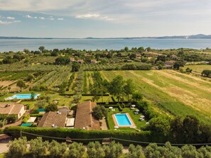 An aerial view of a property with a swimming pool, green lawns, and a view of the sea.
