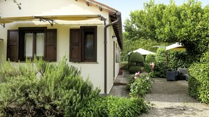 A house with a yellow facade, wooden shutters, and a covered patio area.