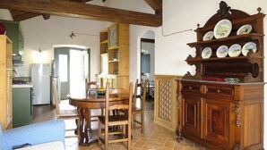 A spacious kitchen with wooden beams, a dining area with a wooden table and chairs, and a wooden cabinet with decorative plates. - Il Podere del Lago (BOL253) by Interhome (Lago di Bolsena)