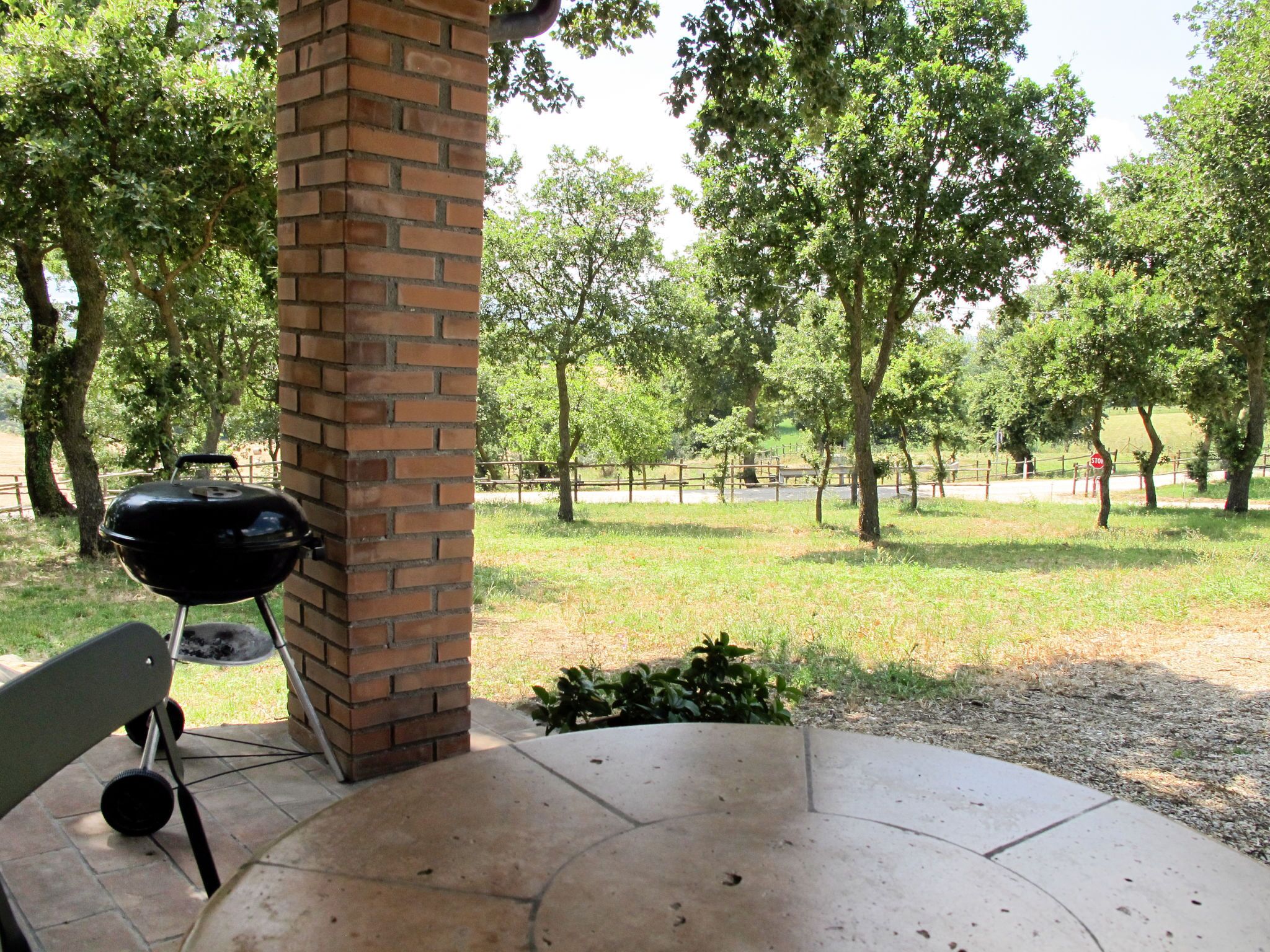 Une terrasse extérieure avec un barbecue en briques et une table en béton.
