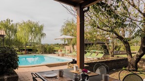 Un espace aménagé au bord de la piscine, avec une table dressée pour les repas, des chaises longues et une vue sur la piscine.