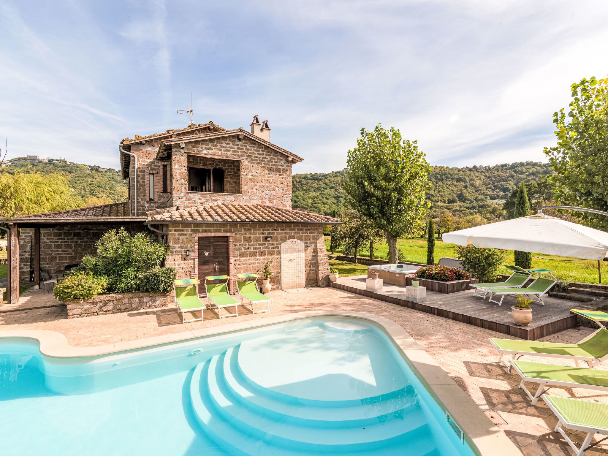A stone villa with a swimming pool, outdoor seating, and a view of the hills.