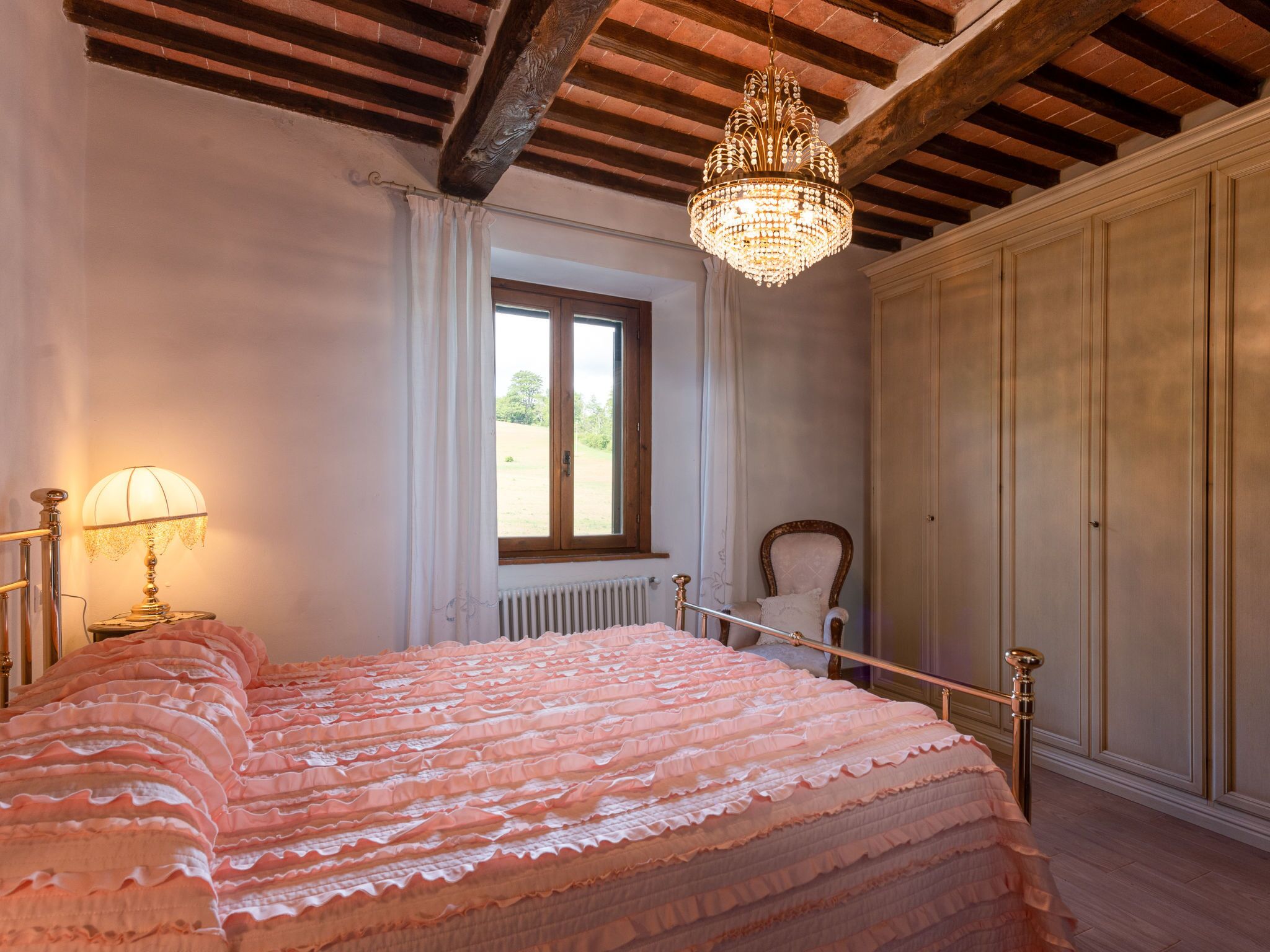 Ein Schlafzimmer mit einem Bett, einer Deckenleuchte, einem Fenster und einer Heizung.