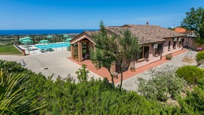 Une villa avec piscine, un espace salon extérieur couvert et une vue sur la mer.