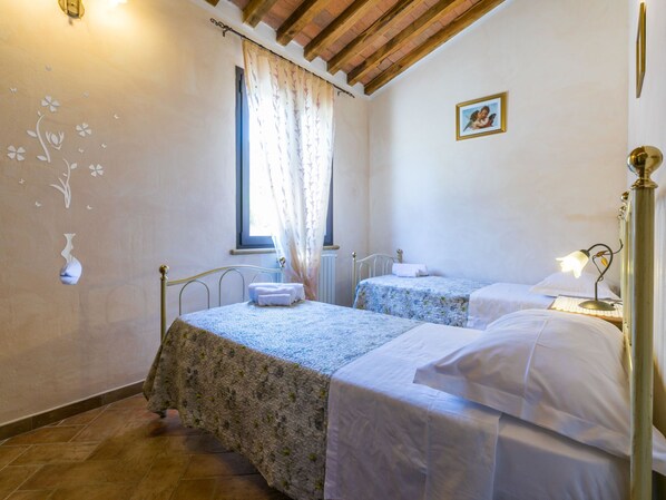 A room with two beds, a window with curtains, a radiator, and a wall with a flower decal. - Il Corbezzolo by Interhome (San Vincenzo)