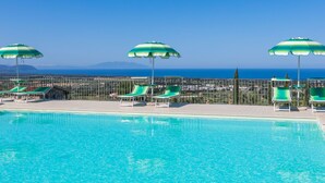 A pool with clear blue water, surrounded by green and white striped umbrellas and lounge chairs. - Il Corbezzolo by Interhome (San Vincenzo)