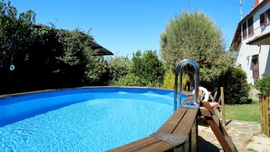 Ein Schwimmbad mit Holzterrasse und Metallleiter.
