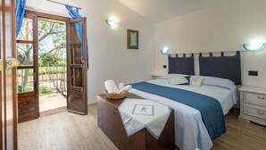 Ein Schlafzimmer mit einem Bett, Nachttischen, einem Beistelltisch, einer Holzkommode, einem Korb und einer Tür zu einem Außenbereich.