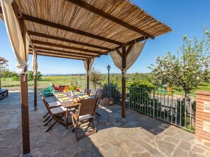 An outdoor patio with a wooden pergola, stone flooring, and a table set for dining. - Bellosguardo by Interhome (Roccastrada)