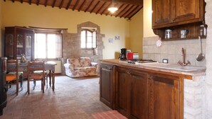 Una cocina rústica con armarios de madera, pared de piedra y salpicadero de azulejos.
