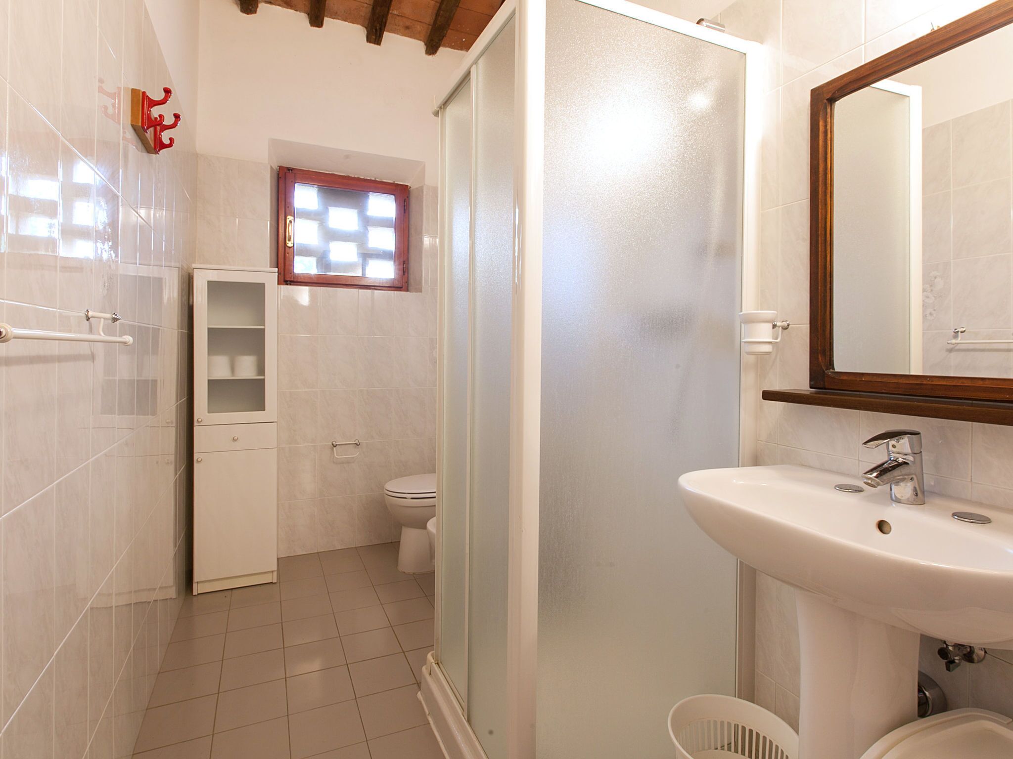 Et badeværelse med toilet, vask og bruseområde.