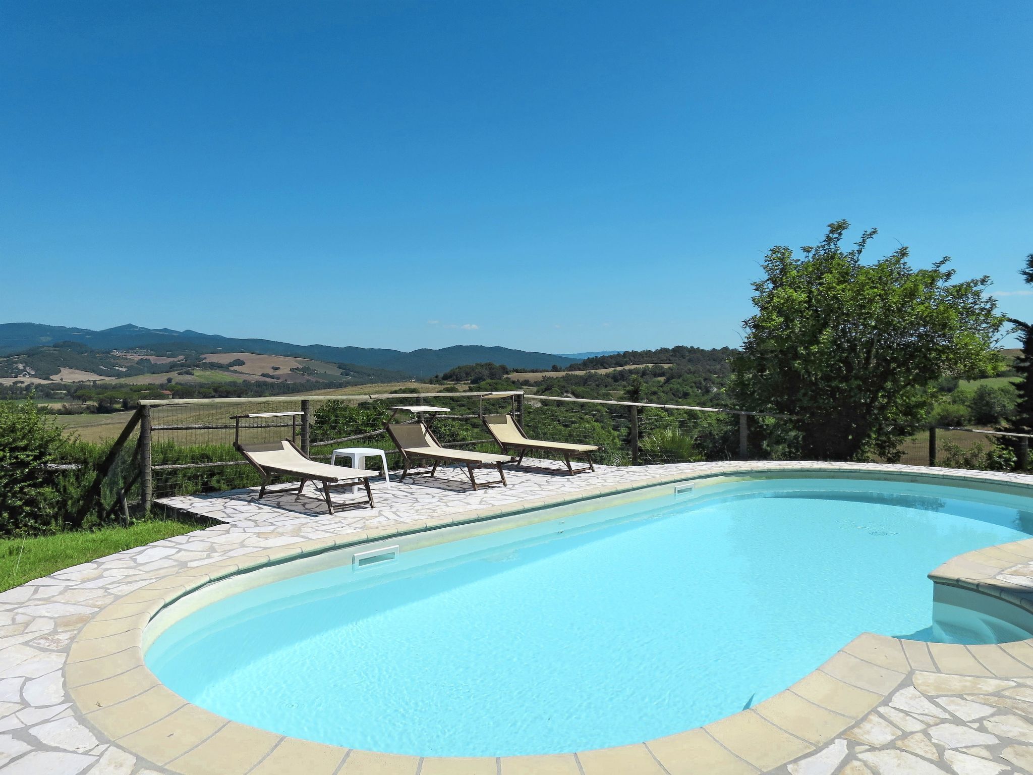 Une piscine dotée de chaises longues et offrant une vue sur la campagne.