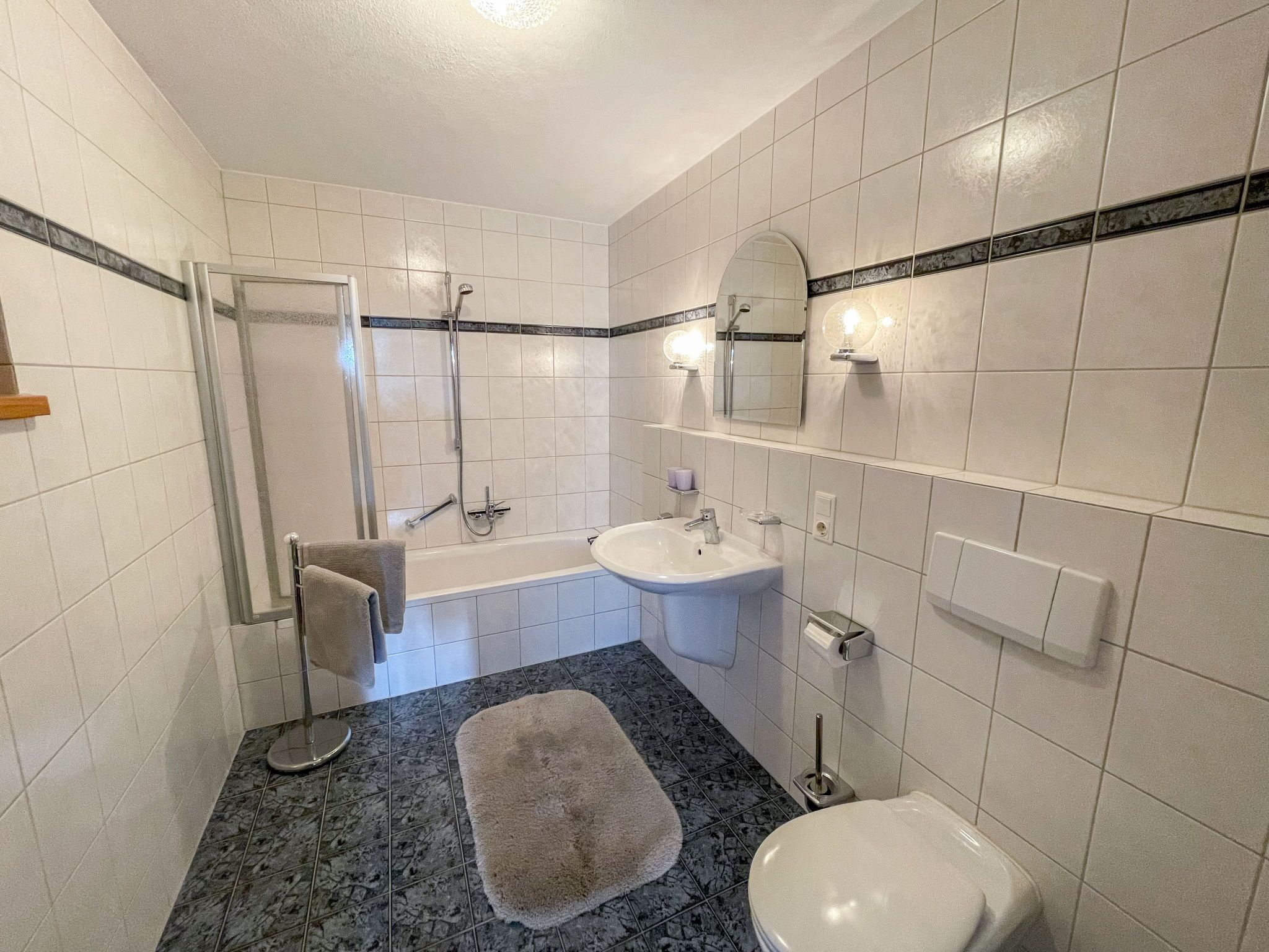 A bathroom with a shower, sink, and toilet.