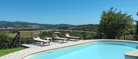 A swimming pool with lounge chairs and a view of the countryside.
