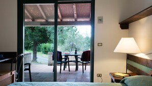Un dormitorio con cama, escritorio y silla. Fuera de la habitación, hay una mesa con sillas.