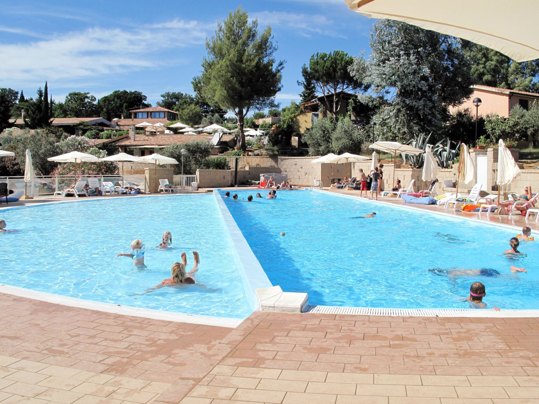 A swimming pool with multiple lanes, surrounded by lounge chairs and umbrellas.