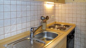 A kitchen with a stainless steel sink, a stove with four burners, and wooden cabinets. - Apartment Harms by Interhome (Horumersiel)