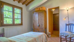 Un dormitorio con cama, armario de madera y una silla.