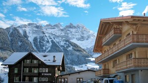 Un bâtiment traditionnel en bois, sur lequel on peut lire l’inscription « Saint-Joseph », avec une chaîne de montagnes en arrière-plan.