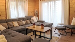 Un salon chaleureux avec un canapé d’angle, une petite table et deux fauteuils.