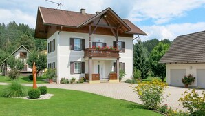 A two-story house with a balcony, surrounded by a well-maintained lawn and garden. - Wiegele by Interhome (Velden am Wörthersee)