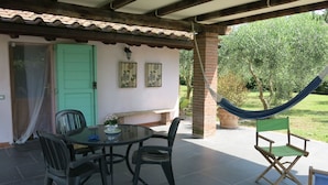 An outdoor patio with a table and chairs, a hammock, and a green door.