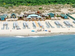 An aerial view of a beachside resort with multiple buildings, rows of beach chairs, and umbrellas. - Cosmopolitan Golf (TIR280) by Interhome (Tirrenia)