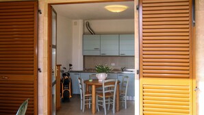 Een keuken met een eettafel, stoelen, een spoelbak en kastjes.
