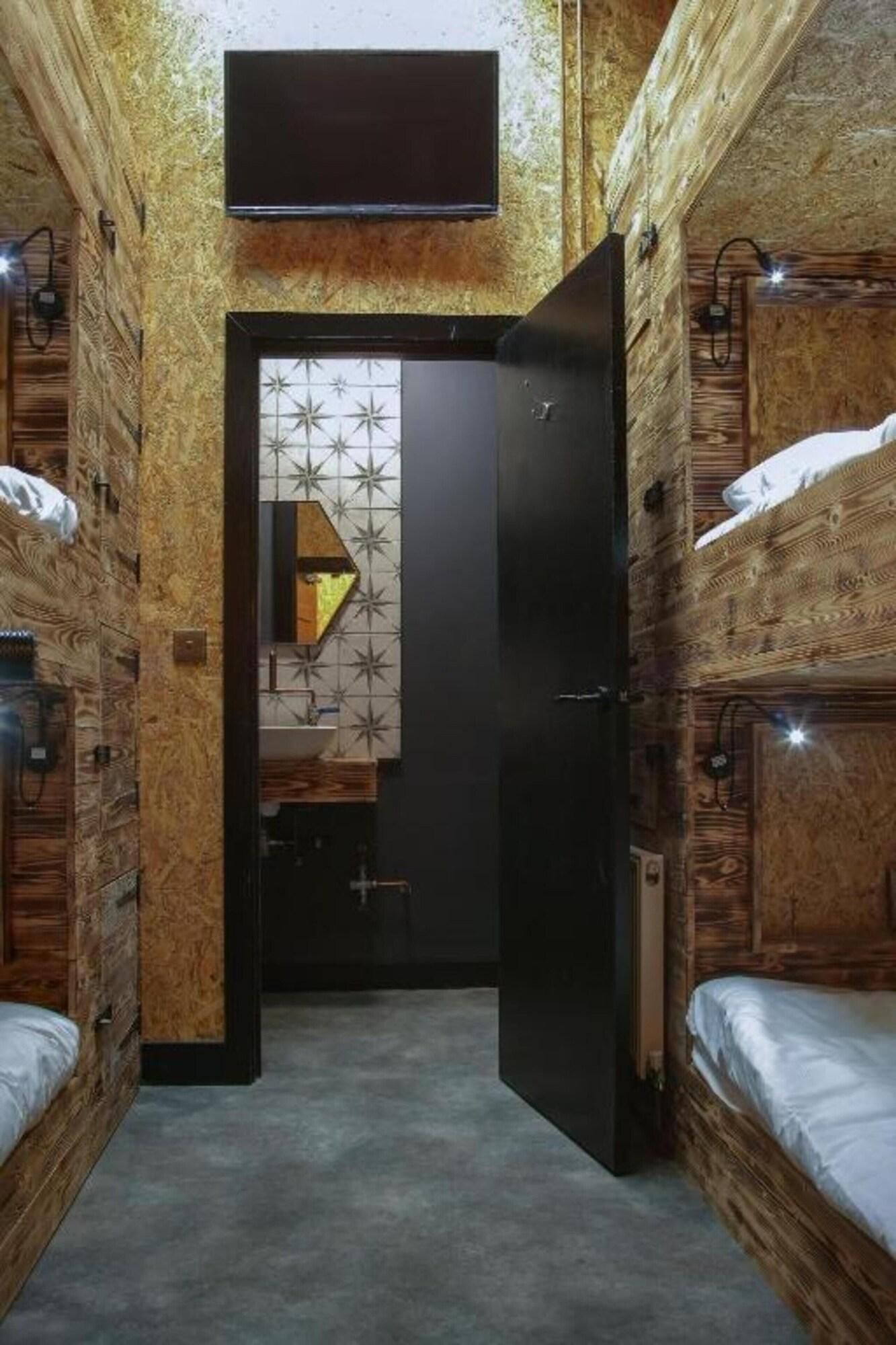 A compact room with bunk beds, a small kitchenette, and a tiled backsplash.