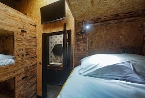 A compact room with wooden walls, a bunk bed, a small sink, and a mirror. - The Studio (Blackpool)