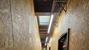 Un pasillo con paredes de madera y alfombra gris, que conduce a una puerta con el letrero 'PLAY'.