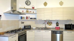 Eine moderne Küche mit Gasherd, Backofen, Geschirrspüler, Mikrowelle und Spüle. Auf den Regalen stehen Dekorationen und an der Wand hängt eine Uhr.