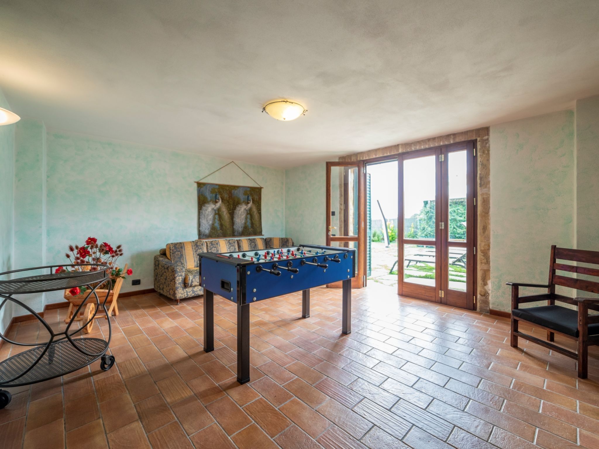 A spacious room with a foosball table, a sofa, and a dining table with chairs.