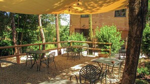An outdoor patio area with tables and chairs, surrounded by trees and a brick building in the background. - Casa alle Vacche by Interhome (San Gimignano)